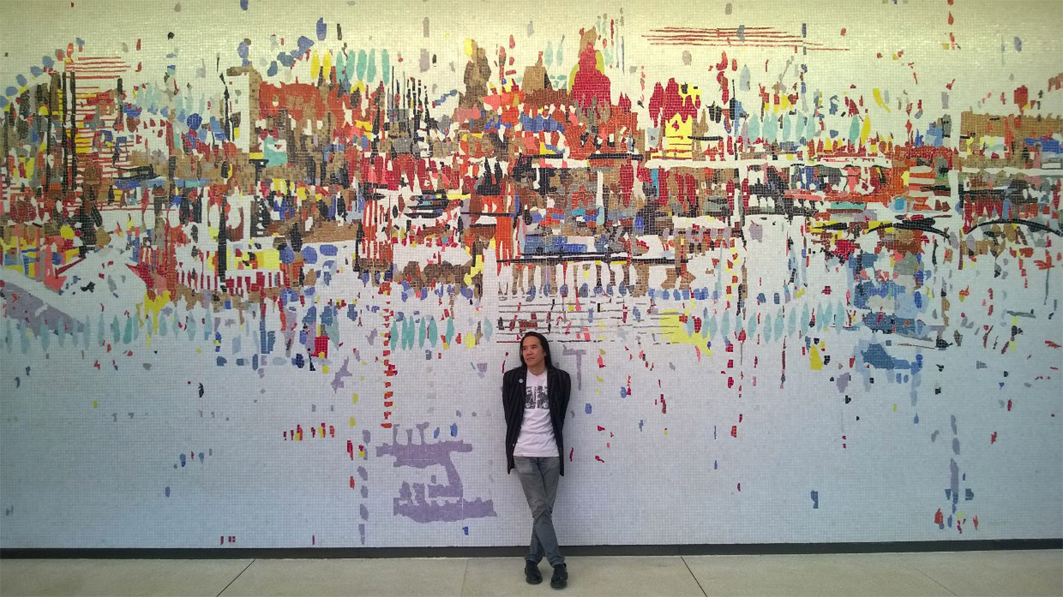 Corey Oada standing in front of Wayne Thiebaud's Water City mural