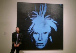 Corey Okada with Andy Warhol's Self-Portrait (1986) at Andy Warhol: Portraits; Crocker Art Museum, Sacramento CA (2016).